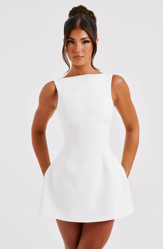 Woman wearing a white sleeveless dress against a plain background