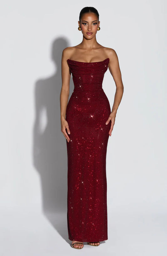 Woman wearing a strapless burgundy evening gown with sequin details on a white background