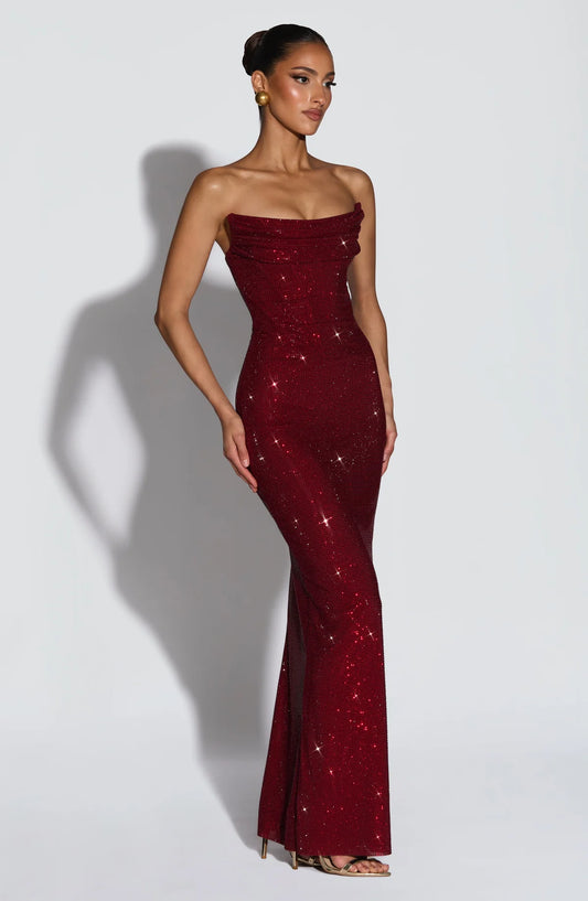Woman wearing a strapless burgundy evening gown with sequin details on a white background